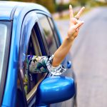 Young woman driving car at countryside , put her hand out of the car enjoy her freedom , making good yo science by her hand, travel vacation concept.